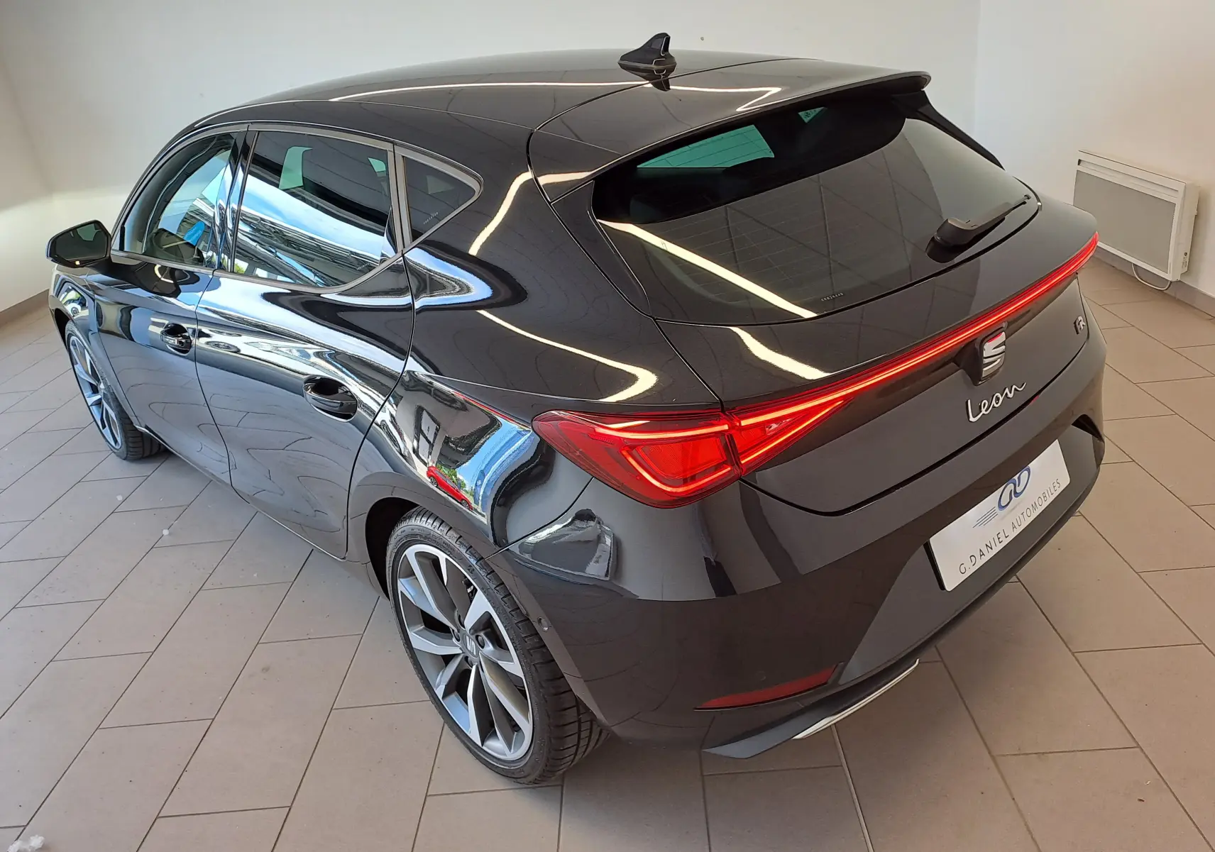Vue 3/4 arrière droite d'une SEAT Leon 2024 noir minuit avec feux arrière LED et jantes alliage distinctives.
