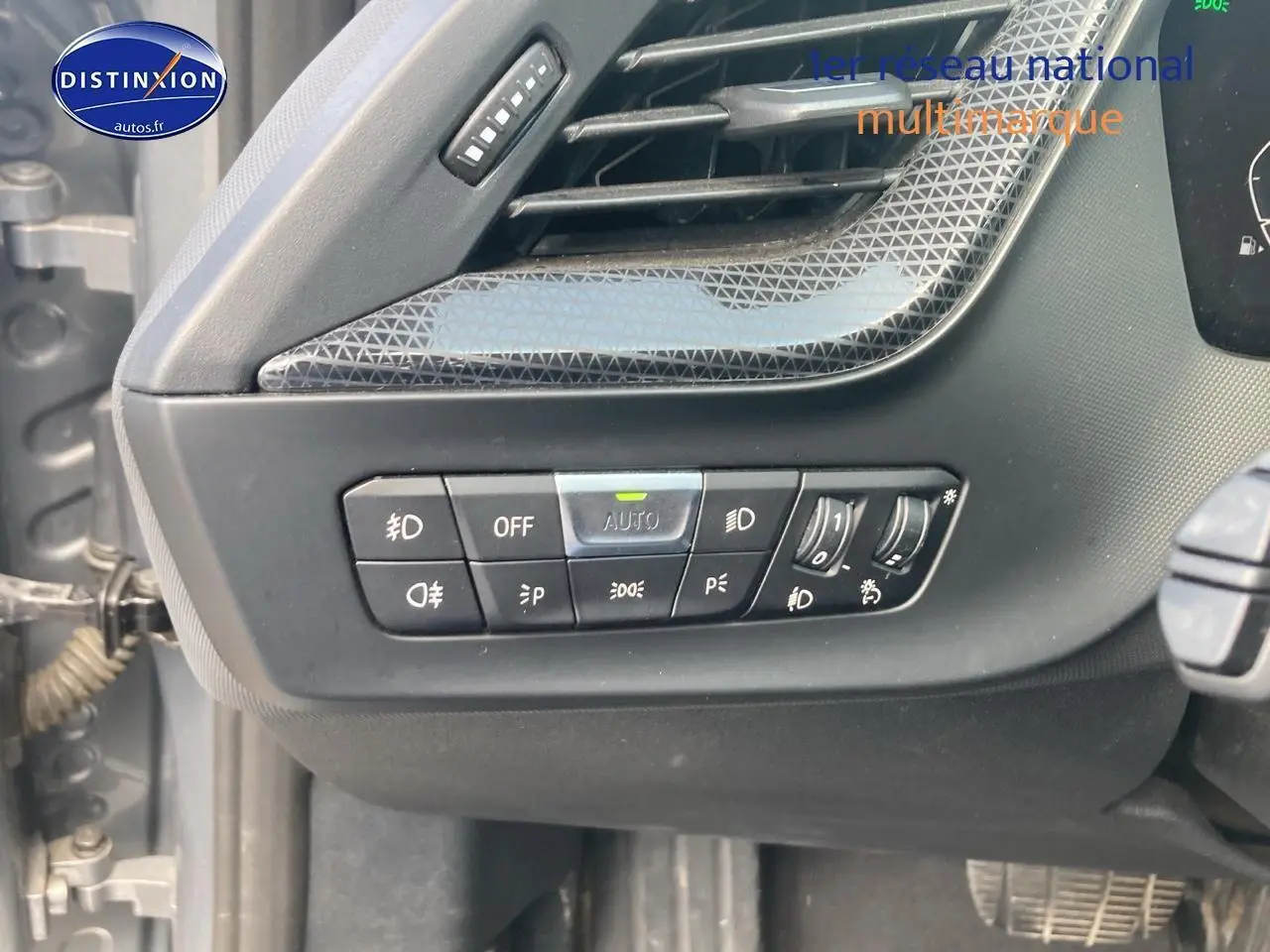 Gros plan sur les commandes d'éclairage à gauche du volant dans l'habitacle d'une BMW Série 1 gris foncé 2023.