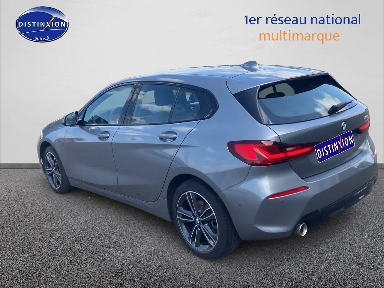 BMW Série 1 gris foncé vue 3/4 arrière droit, avec jantes alliage 17 pouces et feux arrière LED distinctifs.