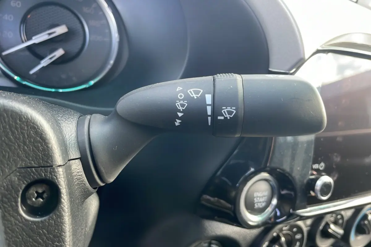 Gros plan sur la commande d'essuie-glace du Toyota Hilux 2025, avec tableau de bord et bouton start/stop visibles.