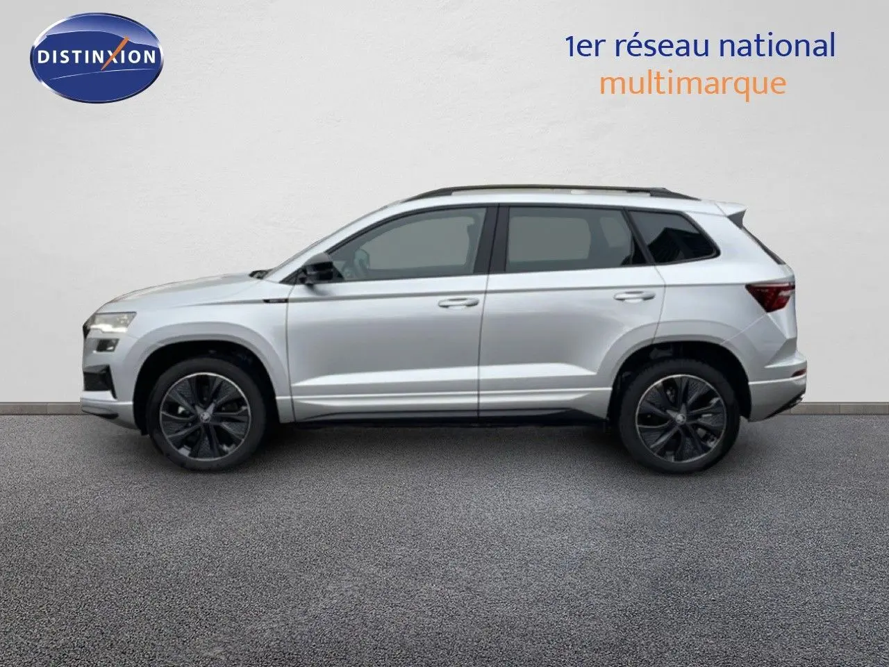 Profil côté gauche d’un Skoda Karoq gris argent métallisé 2025 avec jantes noires et toit ouvrant panoramique.
