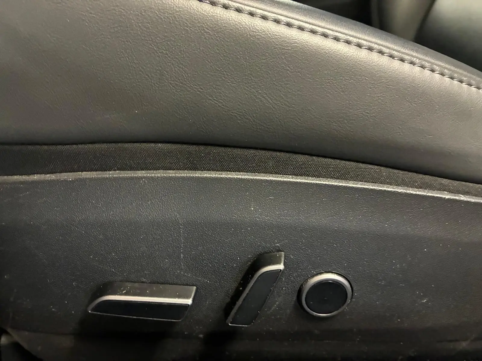 Gros plan sur les commandes de réglage électrique du siège avant d’une Tesla Model 3 blanche, version 2023.
