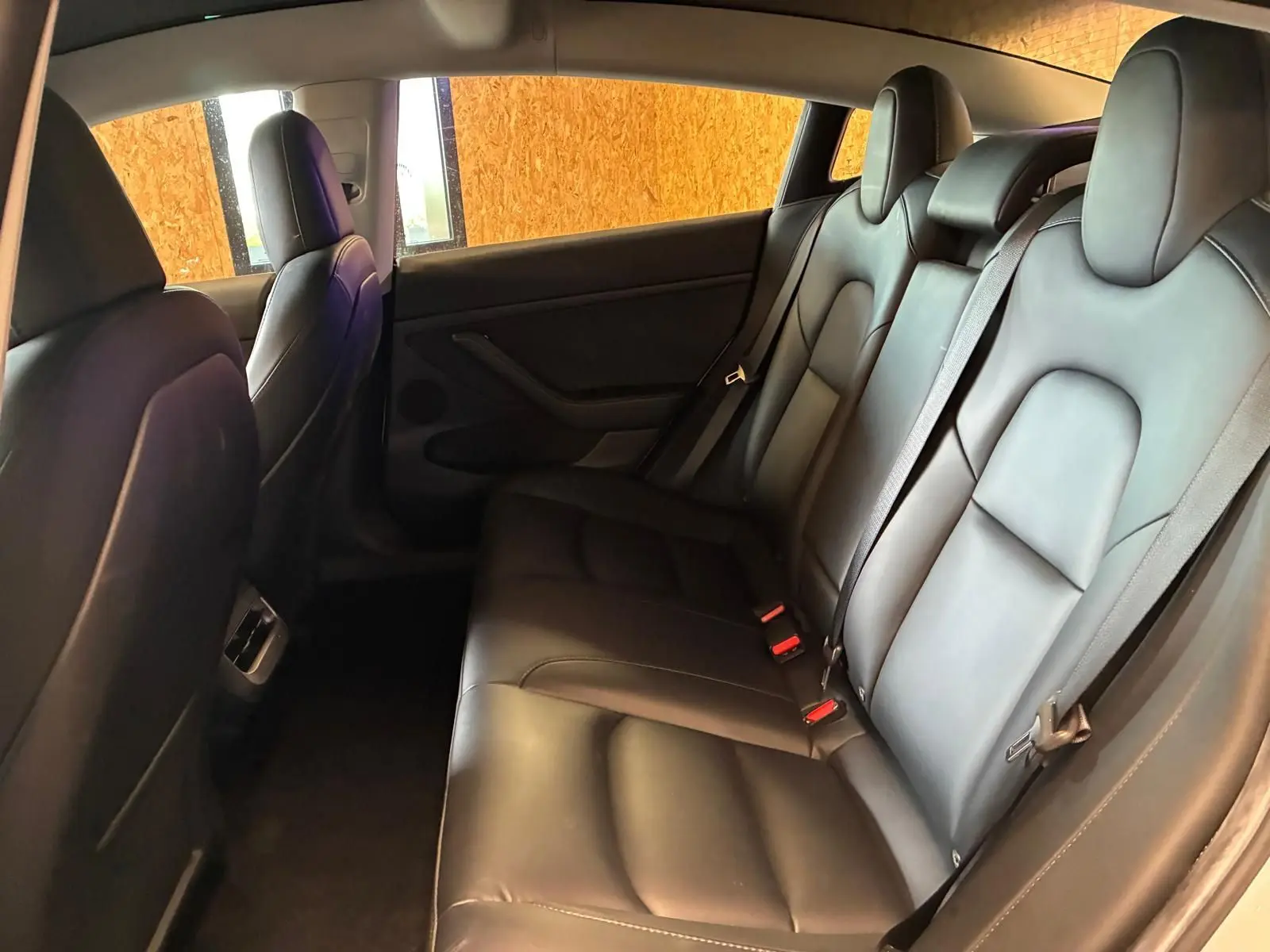 Vue intérieure arrière droite des sièges en cuir noir du Tesla Model 3 blanc 2023, version RWD Standard Plus.