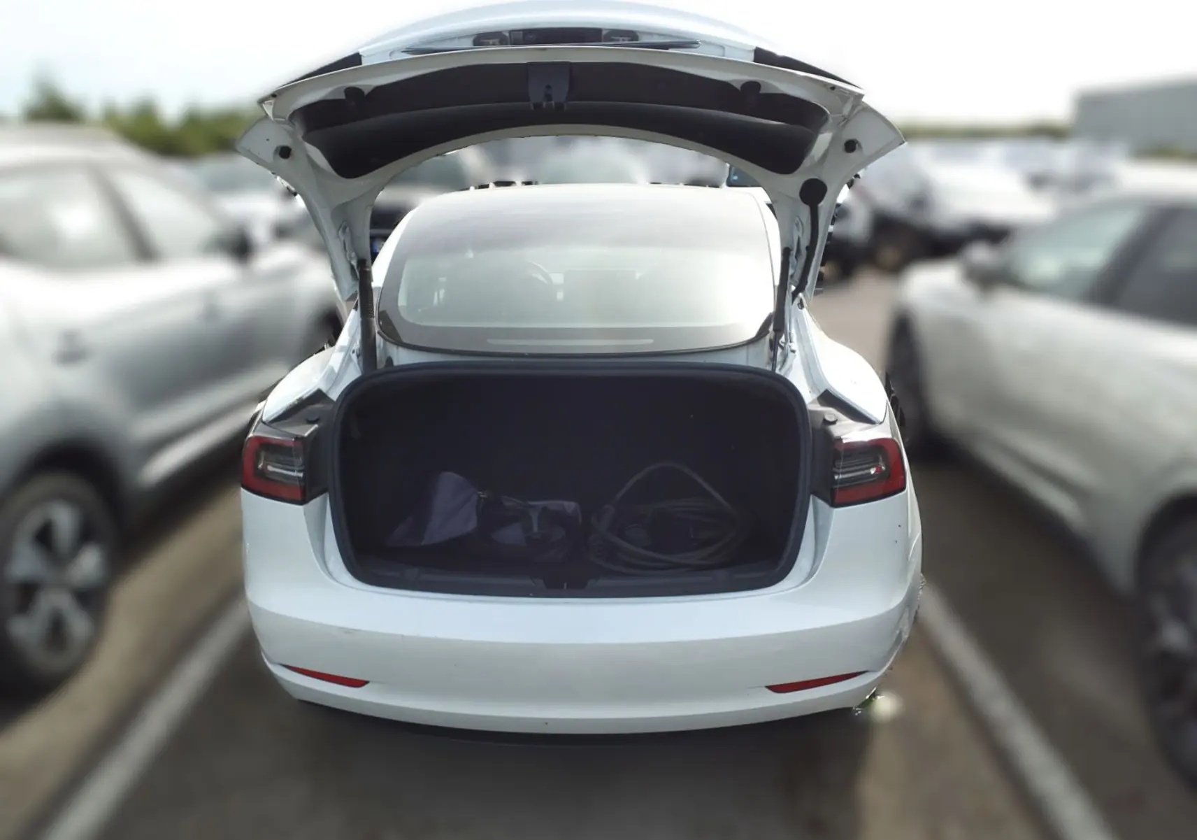 Vue de face d'une Tesla Model 3 blanche RWD 2023, avec phares noirs et plaque d'immatriculation Distinxion.
