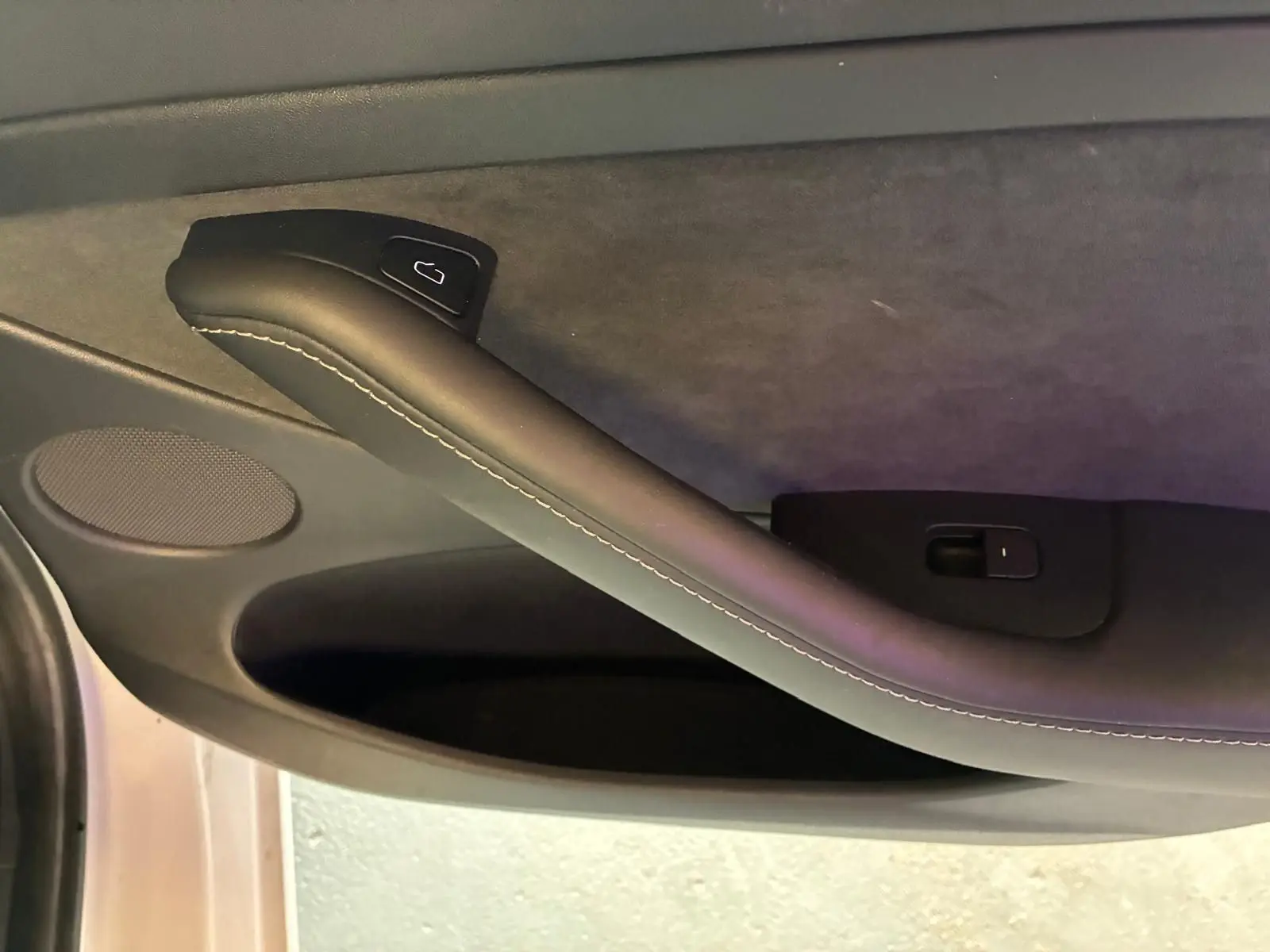 Détail de la poignée intérieure côté gauche de la porte d’une Tesla Model 3 blanche, version 2023.