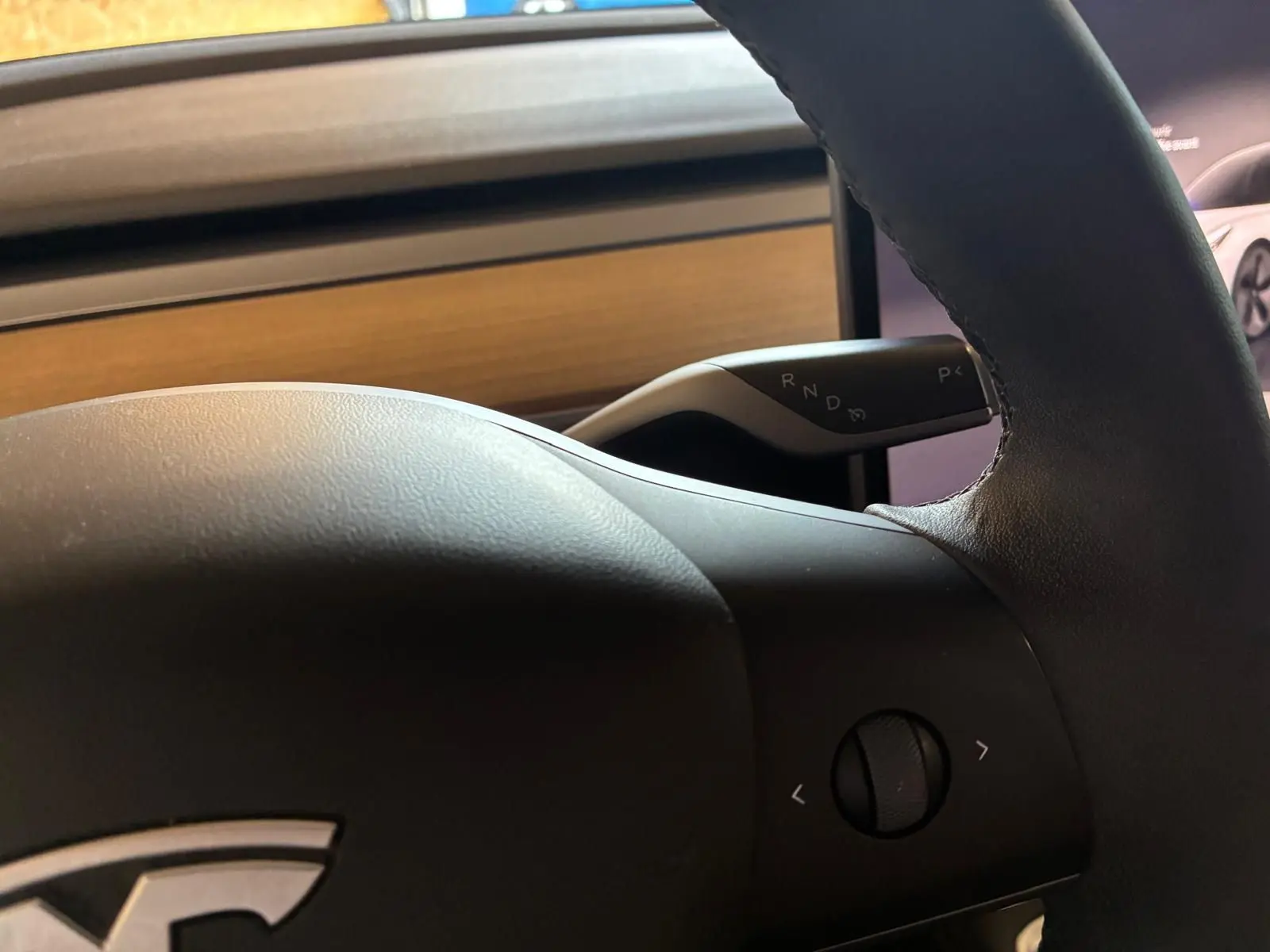 Gros plan sur le volant noir de la Tesla Model 3 blanc, version RWD 2023, avec levier de vitesses automatique visible.