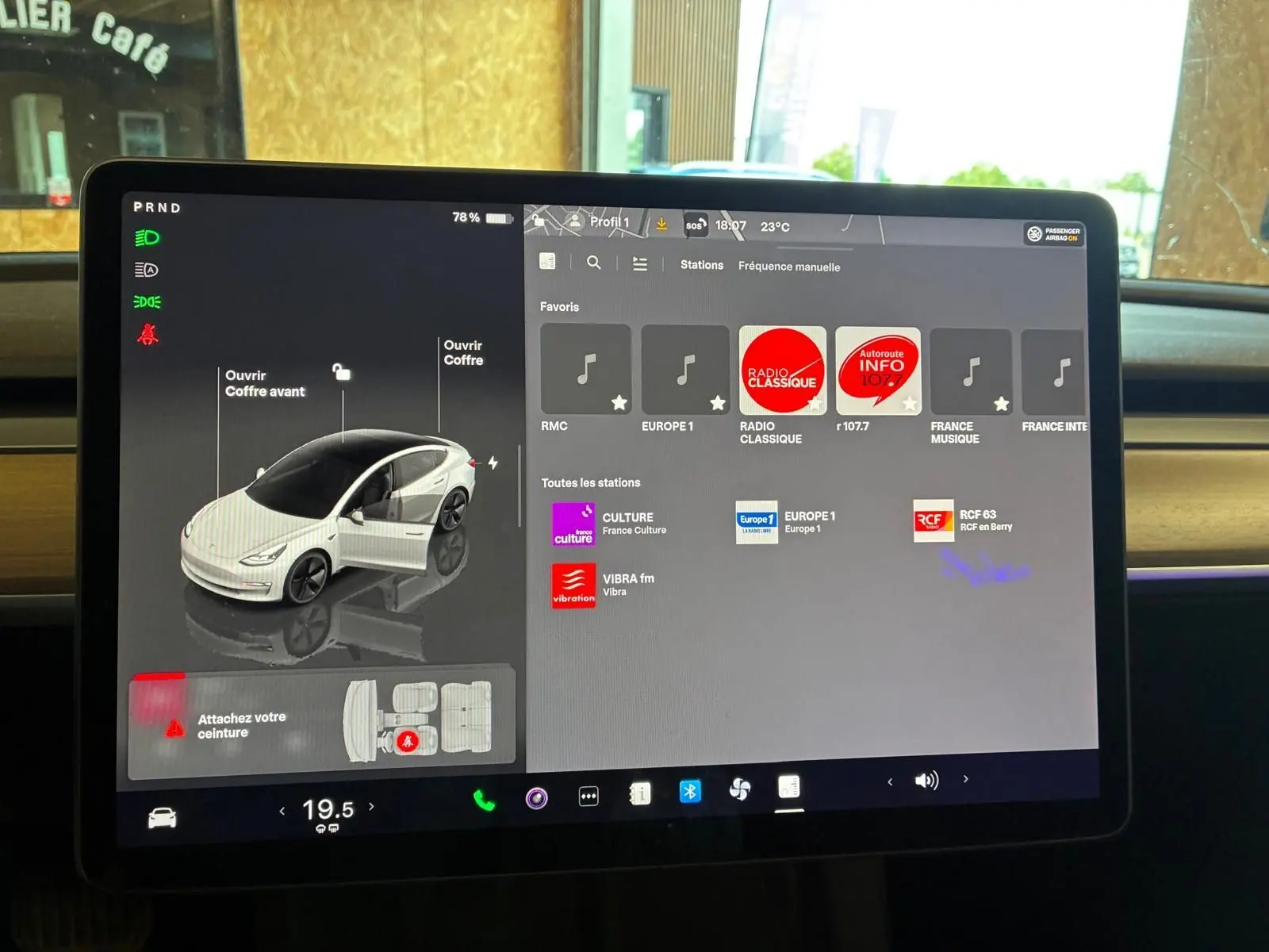 Écran tactile central de Tesla Model 3 blanc 2023 montrant l'interface multimédia et les options de coffre ouvert.