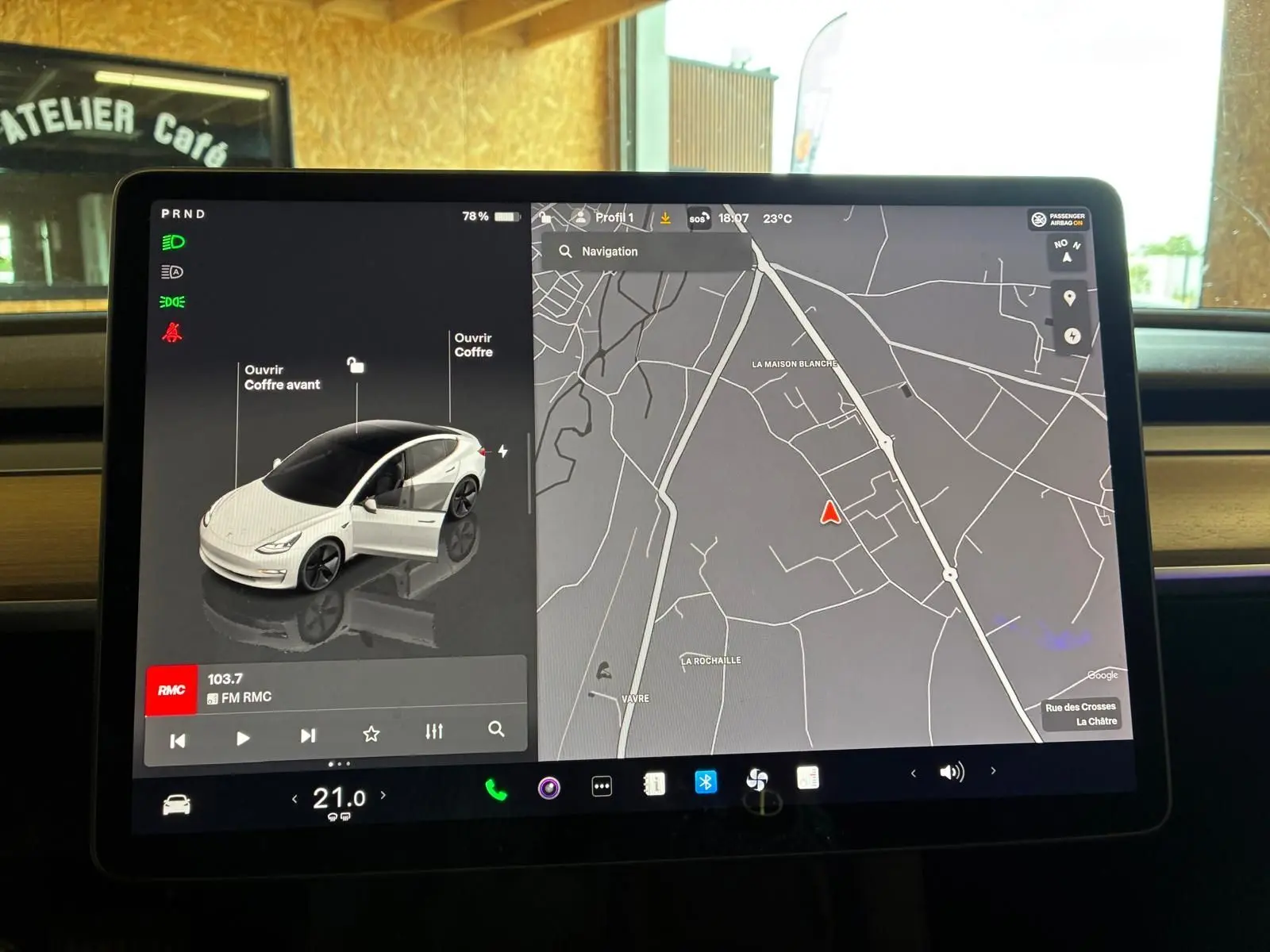 Écran tactile intérieur de Tesla Model 3 blanc, vue frontale de la voiture sur l'interface avec carte de navigation affichée.