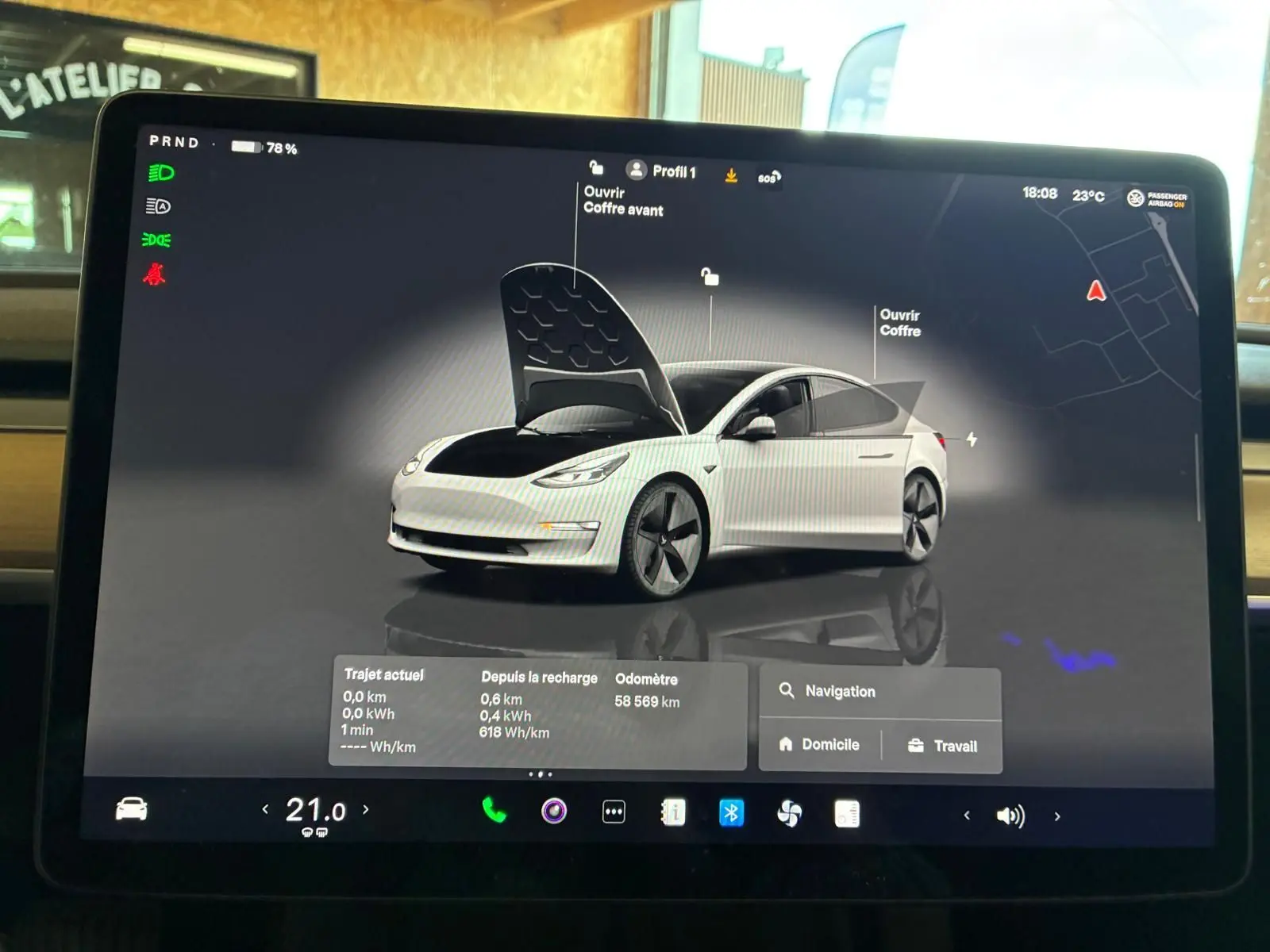 Écran tactile montrant une Tesla Model 3 blanche en 3/4 avant avec capot et coffre ouverts, interface de contrôle.