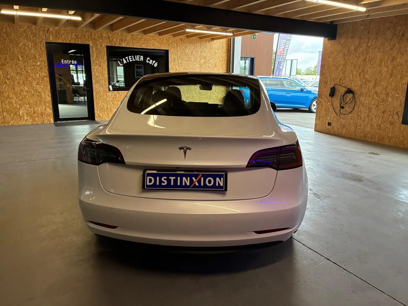Vue arrière d'une Tesla Model 3 blanche RWD 2023, avec feux arrière teintés et plaque d'immatriculation Distinxion.