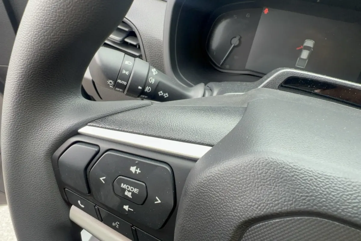 Gros plan sur le volant multifonctions noir de l'Isuzu D-MAX 2026 avec commandes audio et affichage tableau de bord.