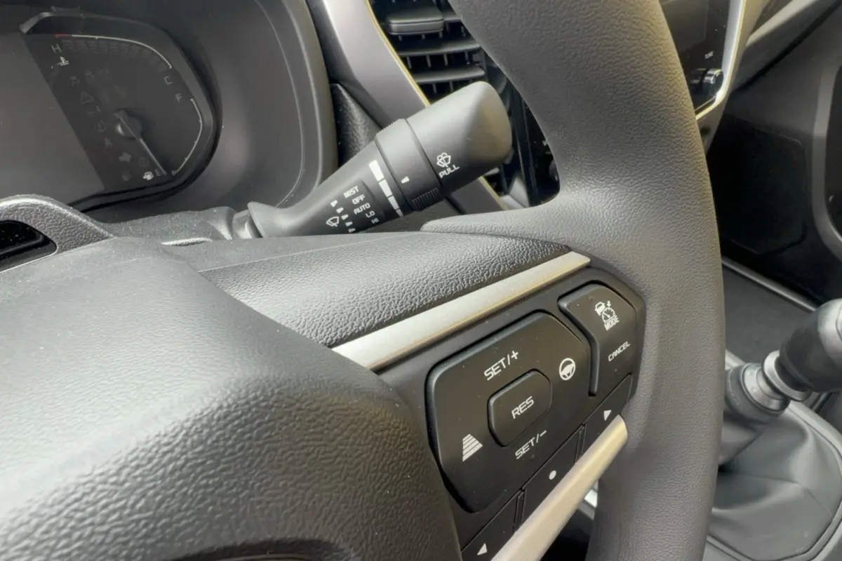 Gros plan sur le volant multifonctions gris foncé de l'Isuzu D-MAX 2.2 TD 164 Space Evolution avec commandes de régulateur.