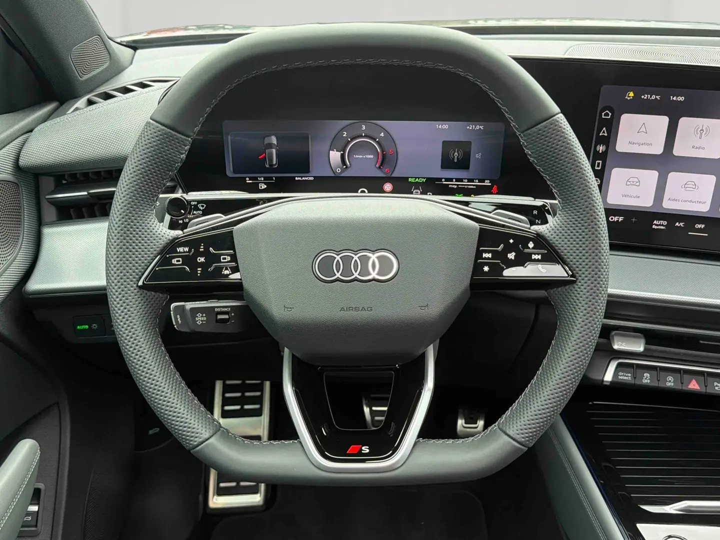 Vue intérieure centrée sur le volant sport cuir gris avec logo S, tableau de bord numérique et écran tactile Audi Q3 Sportback.