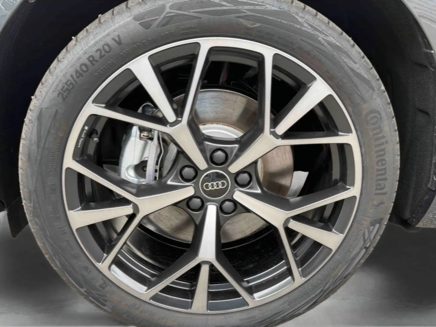 Gros plan sur la jante Audi Sport tripode noire et métal brossé de 20 pouces du Q3 Sportback gris.