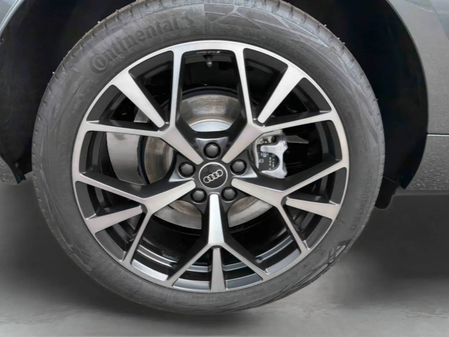 Gros plan sur la jante Audi Sport style tripode à 5 branches noires métalliques du Q3 Sportback gris.