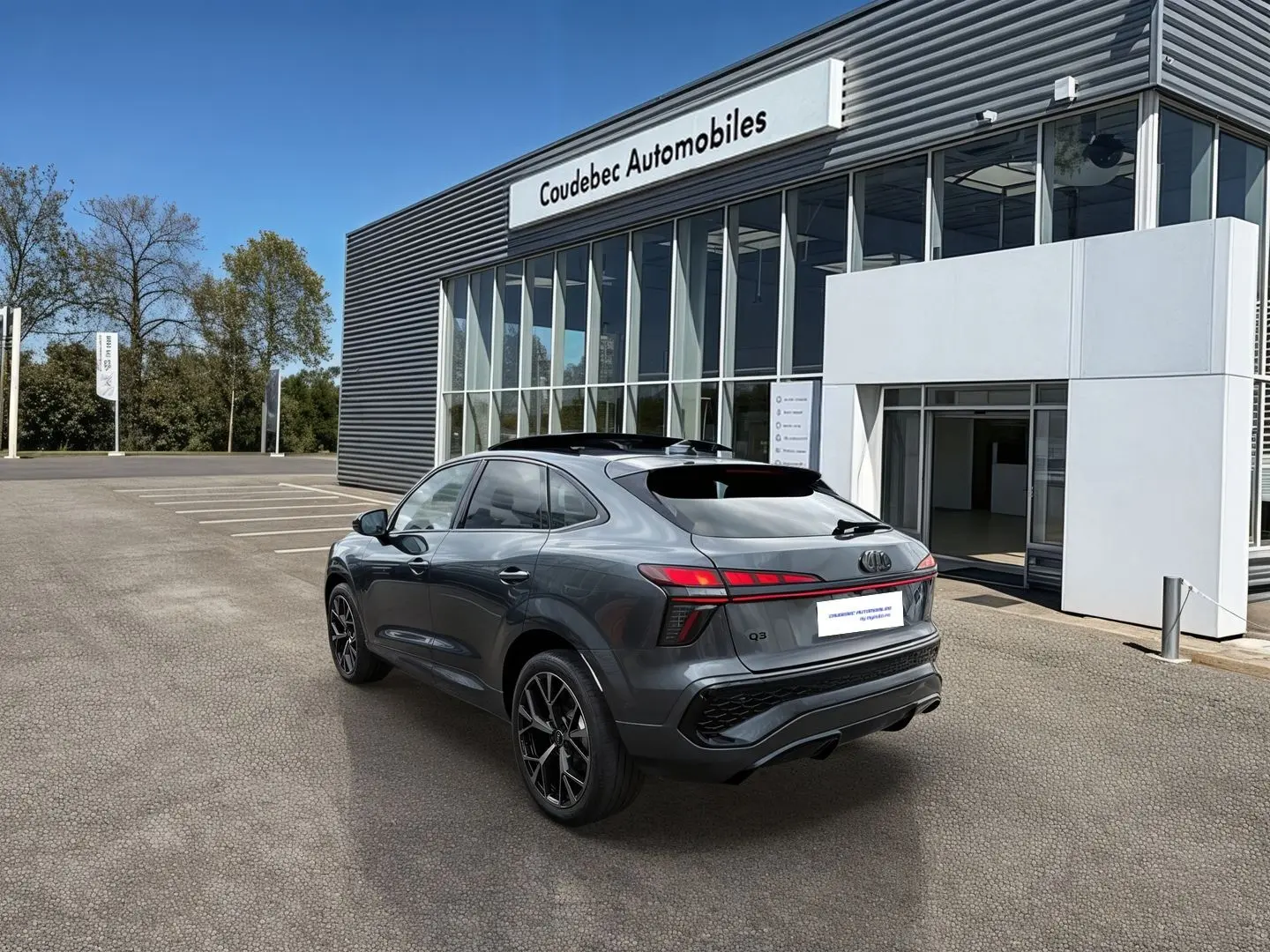 Audi Q3 Sportback gris vue 3/4 arrière droit, avec jantes noires et toit ouvrant panoramique visible.