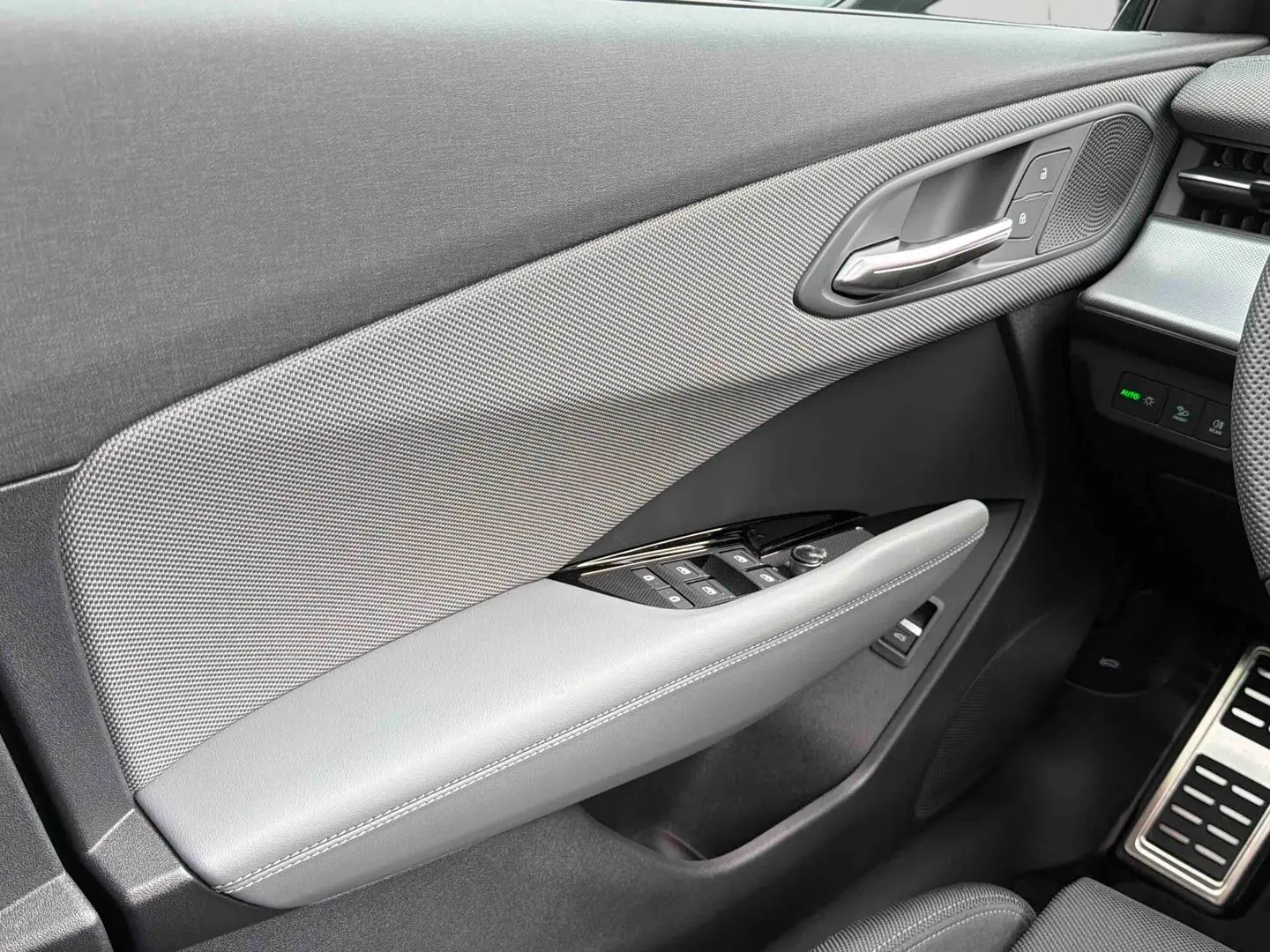 Détail de la porte avant gauche grise de l'Audi Q3 Sportback avec commandes de vitres et poignée chromée.