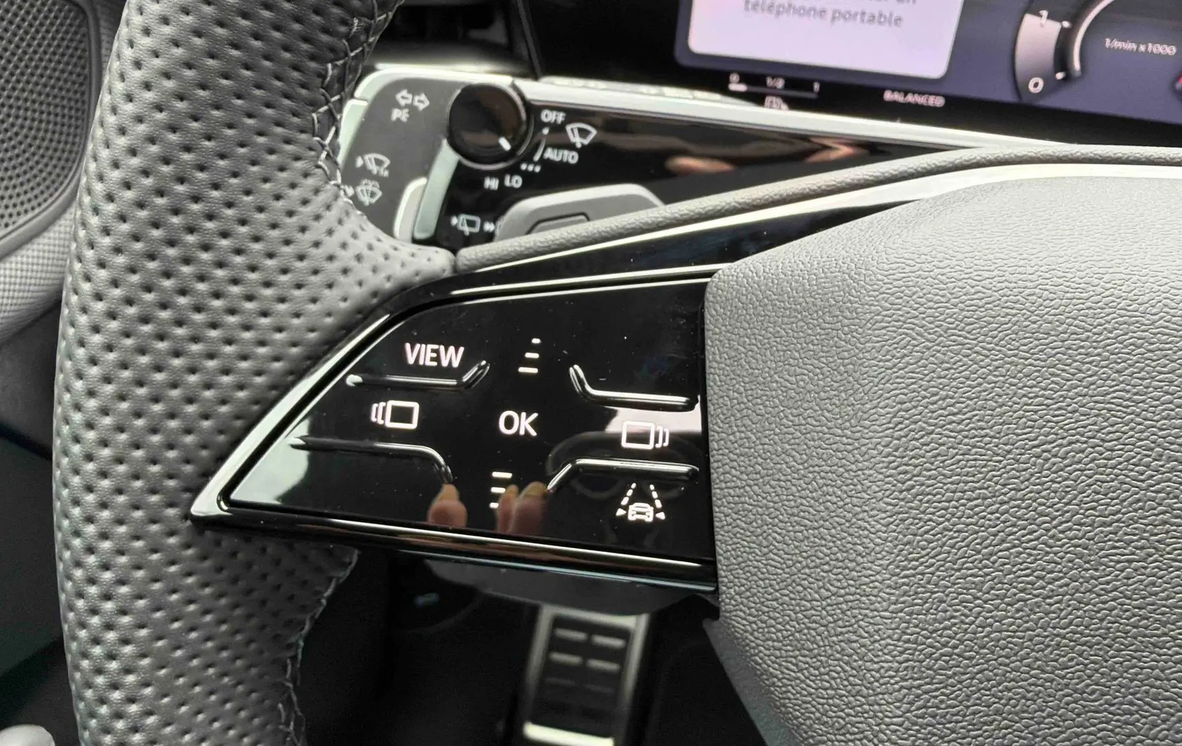 Gros plan sur le volant cuir perforé côté gauche de l’Audi Q3 Sportback gris avec commandes tactiles et affichage numérique.