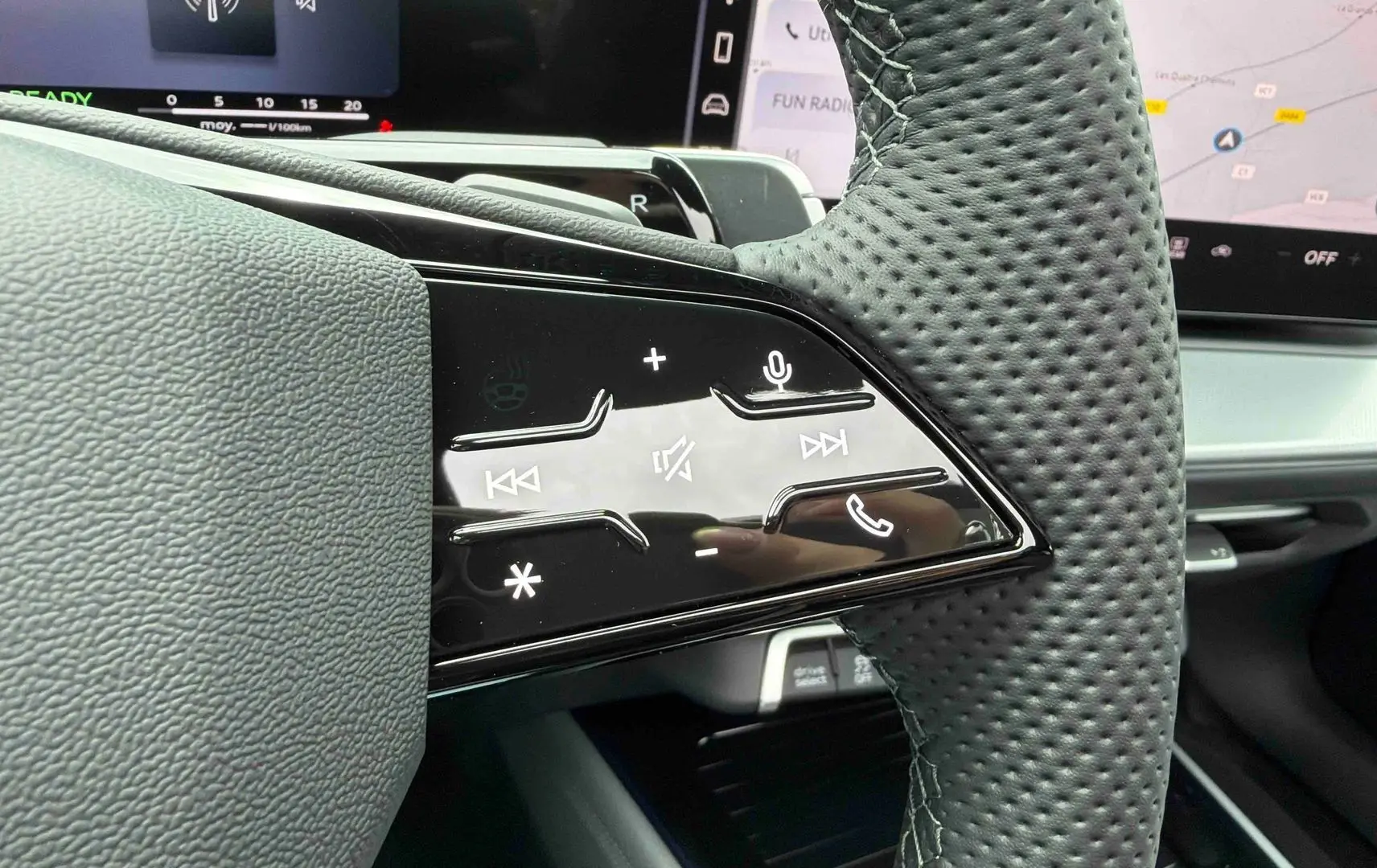 Gros plan sur les commandes tactiles noires du volant perforé côté gauche de l’Audi Q3 Sportback gris.
