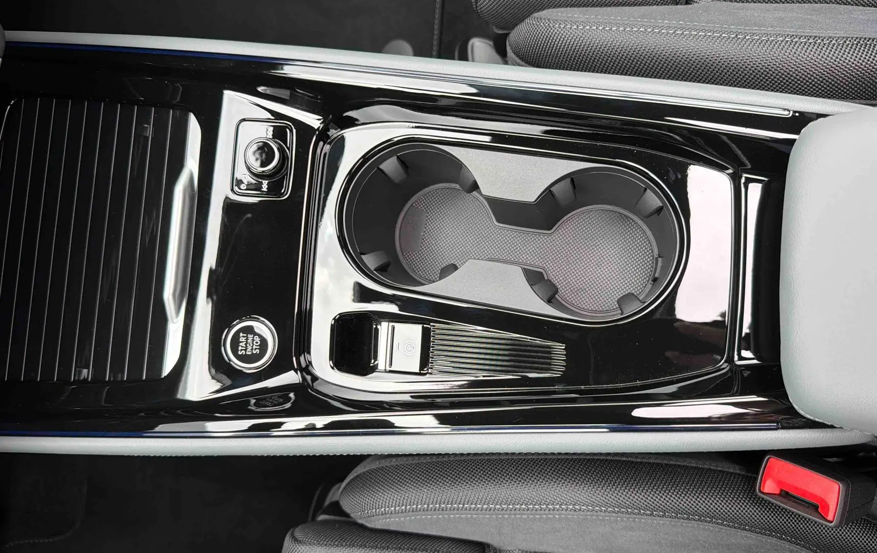 Gros plan sur la console centrale noire brillante avec porte-gobelets et bouton start/stop de l'Audi Q3 Sportback gris.