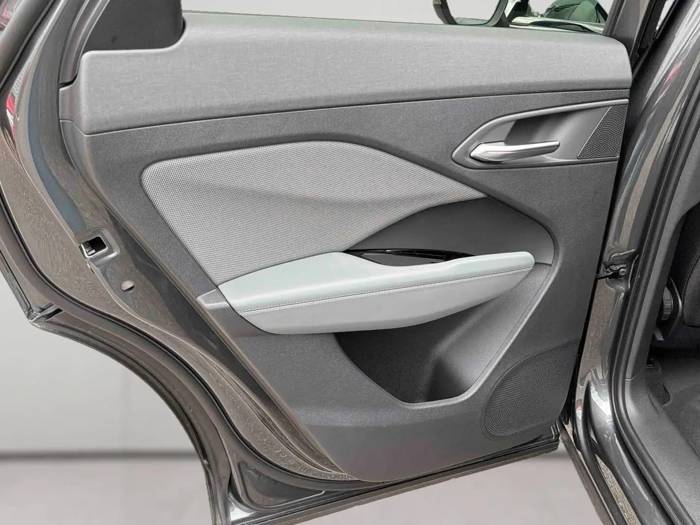 Vue rapprochée de la porte arrière gauche grise de l’Audi Q3 Sportback avec garniture tissu et accoudoir clair.