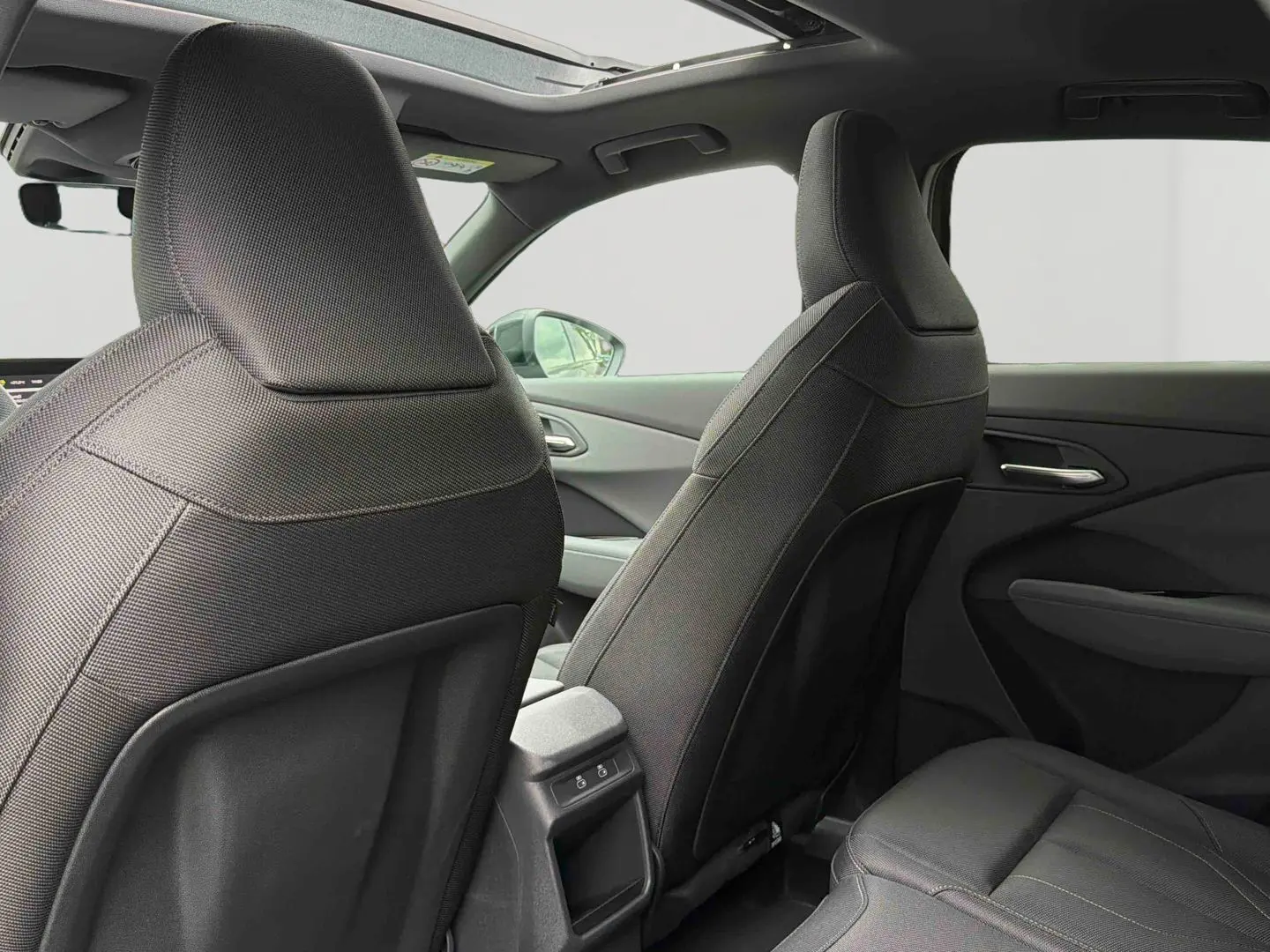 Vue intérieure arrière de l’Audi Q3 Sportback gris, montrant les sièges avant et le toit ouvrant panoramique.