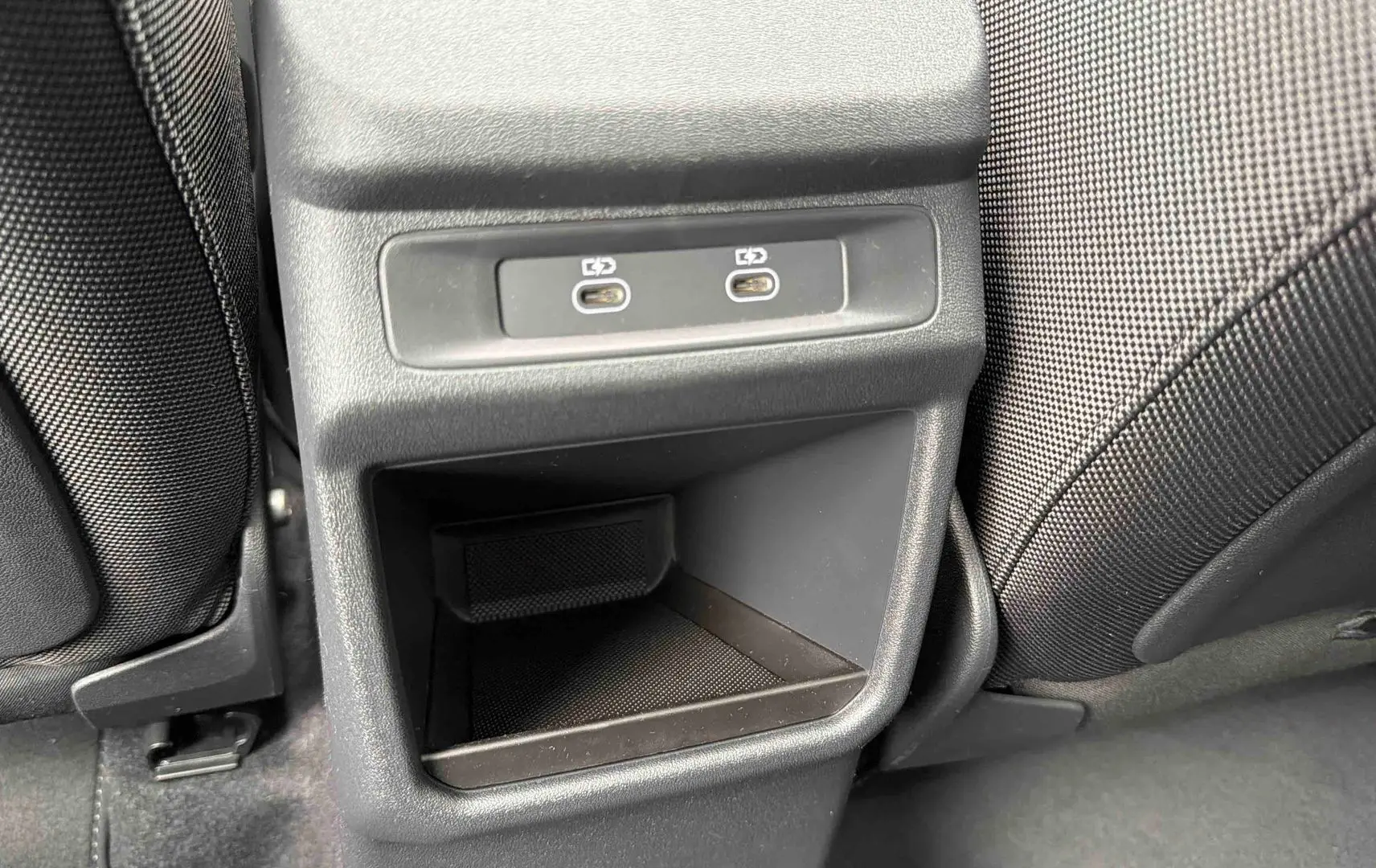 Gros plan sur la console arrière avec deux ports USB-C et rangement, entre les sièges noirs du Q3 Sportback gris.