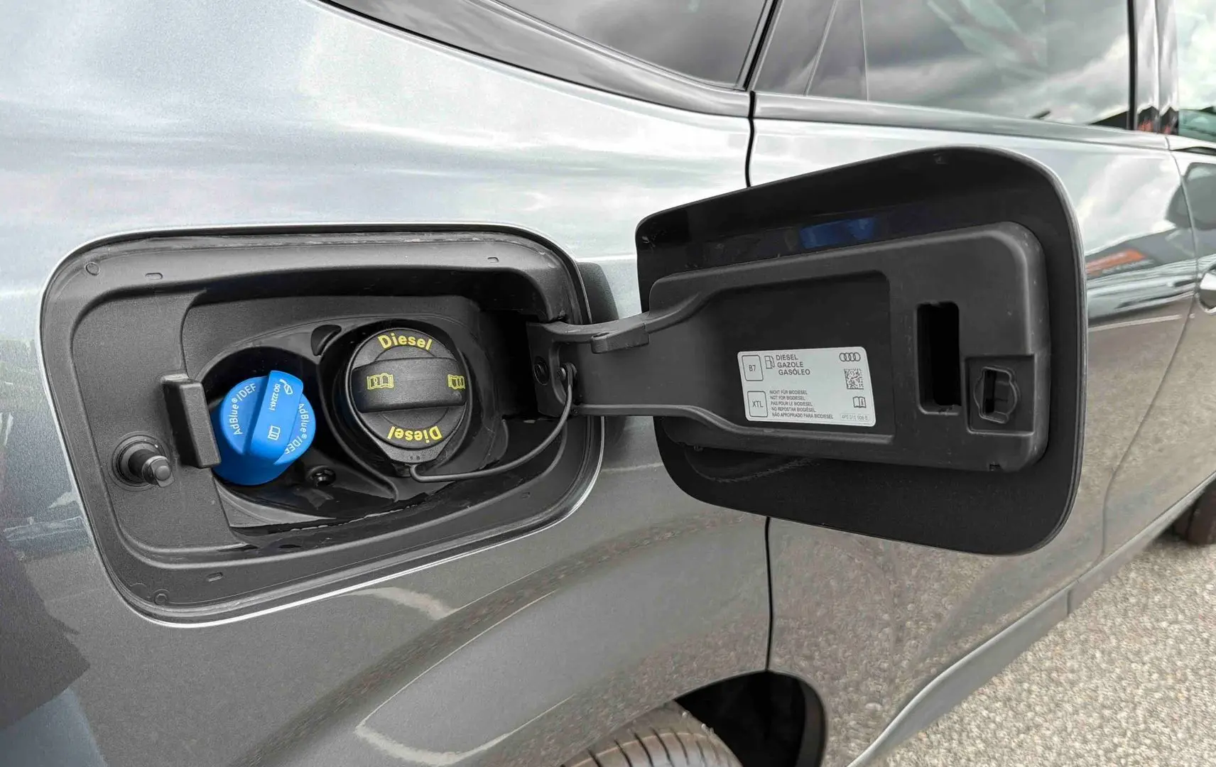 Gros plan sur la trappe à carburant ouverte côté gauche d’un Audi Q3 Sportback gris métallisé.