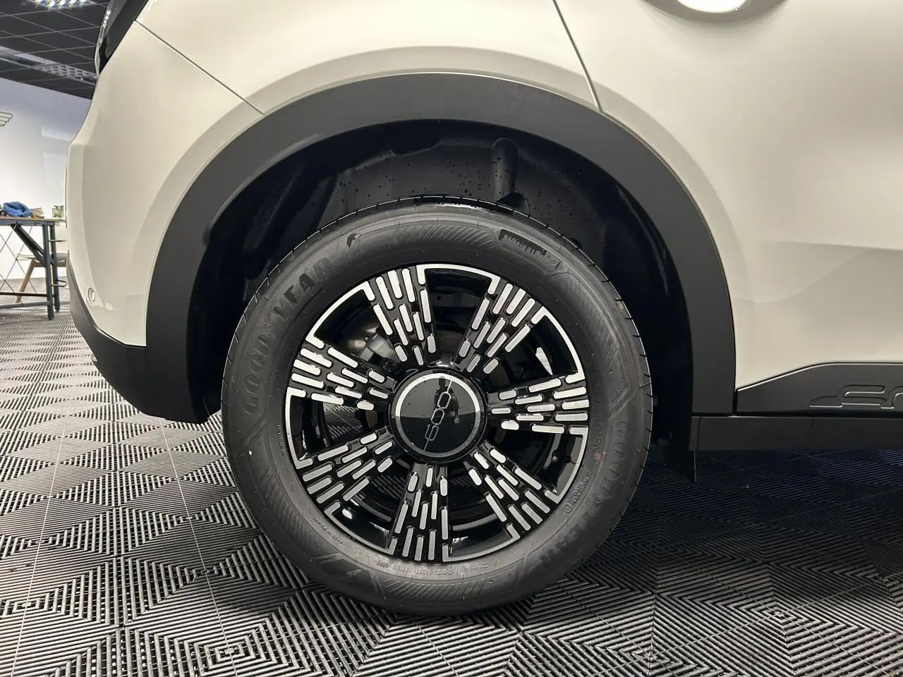 Gros plan sur la roue arrière droite noire et blanche du FIAT 600 blanc, avec jante alliage au design moderne.