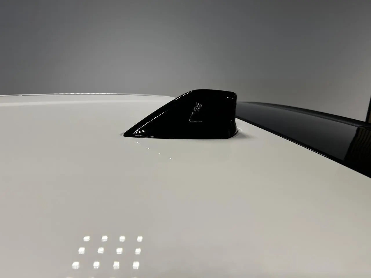 Détail de l'antenne requin noire sur le toit blanc d'une Fiat 600 hybride 2026, vue de dessus rapprochée.
