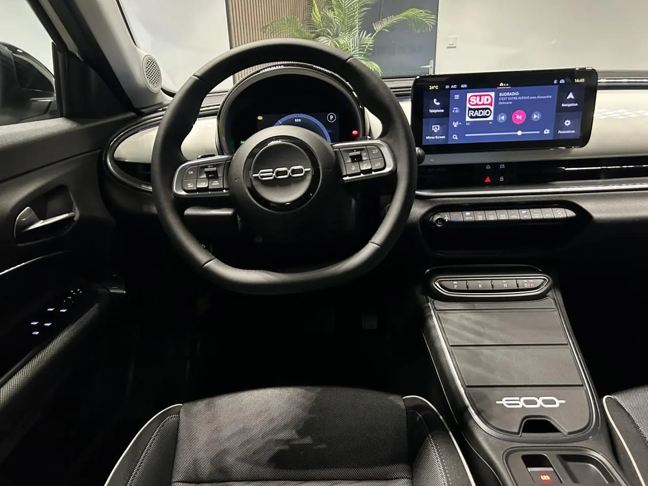 Vue intérieure frontale du tableau de bord et volant noir du Fiat 600 avec écran tactile et console centrale marquée 600.