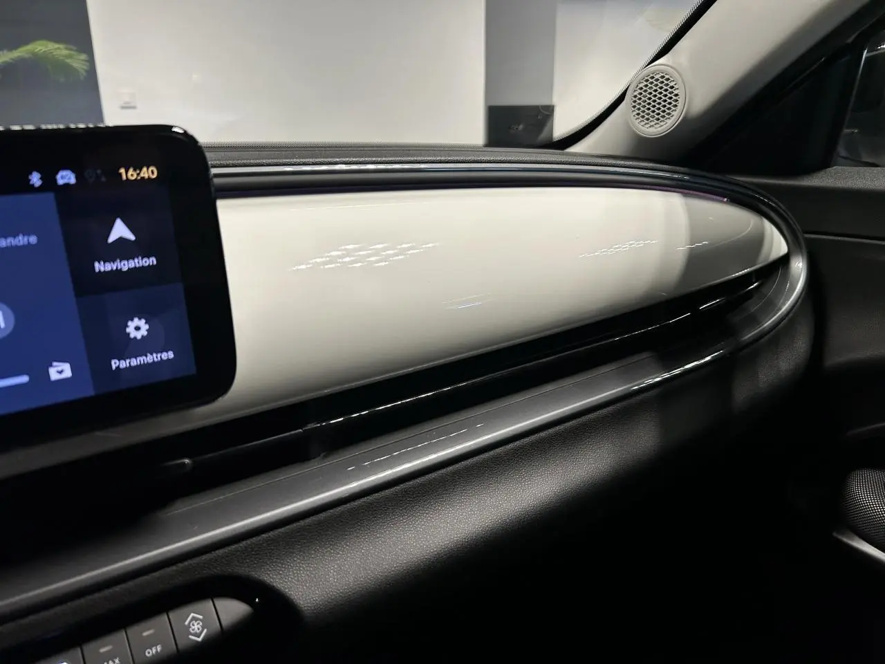 Vue intérieure côté passager du tableau de bord blanc brillant du Fiat 600 1.2 Hybrid avec écran tactile et haut-parleur intégré.