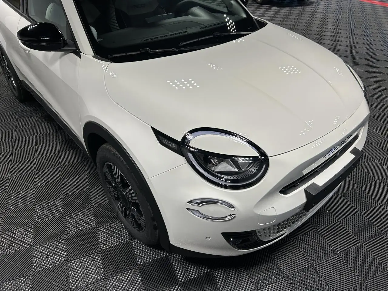 Vue 3/4 avant gauche d'une FIAT 600 blanche avec coques de rétroviseurs noires brillantes et jantes alliage noires.