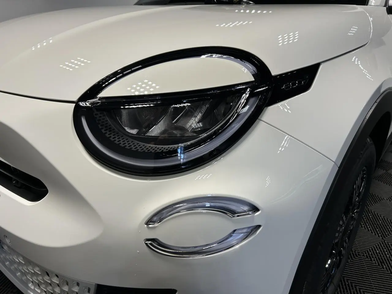 Gros plan sur le phare avant gauche du Fiat 600 blanc avec détails noirs et éclairage LED distinctif.