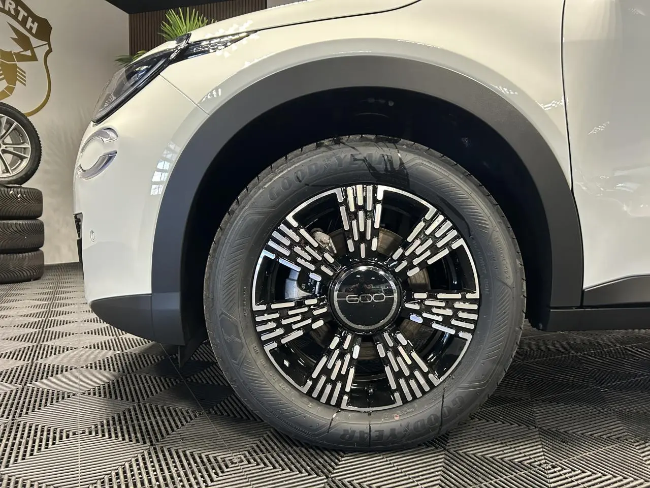 Gros plan sur la roue avant gauche noire et chromée du FIAT 600 blanc avec logo 600 au centre de la jante.