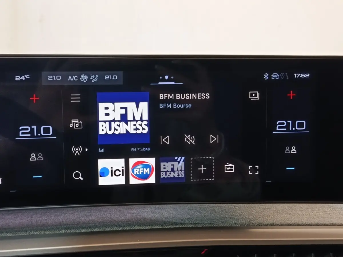 Écran tactile central du Peugeot 5008 gris clair 2026 affichant la radio BFM Business et réglages climatisation à 21°C.