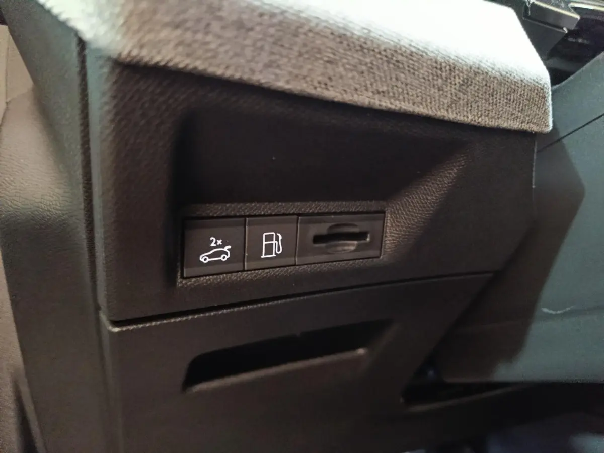 Gros plan sur les commandes d'ouverture du coffre et du bouchon de carburant dans l'habitacle du Peugeot 5008 gris clair.