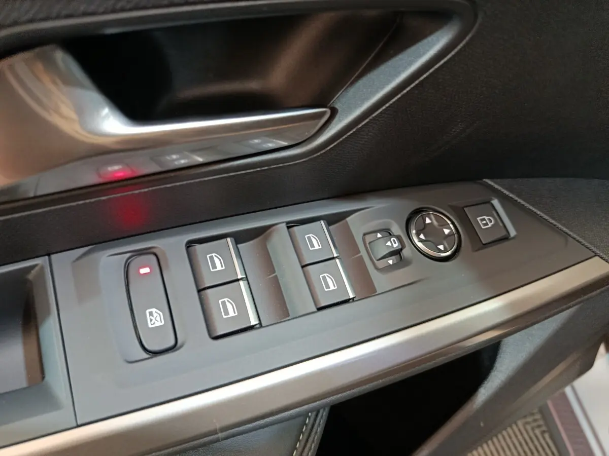 Gros plan sur les commandes de lève-vitres et rétroviseurs côté conducteur du Peugeot 5008 gris clair 2026.