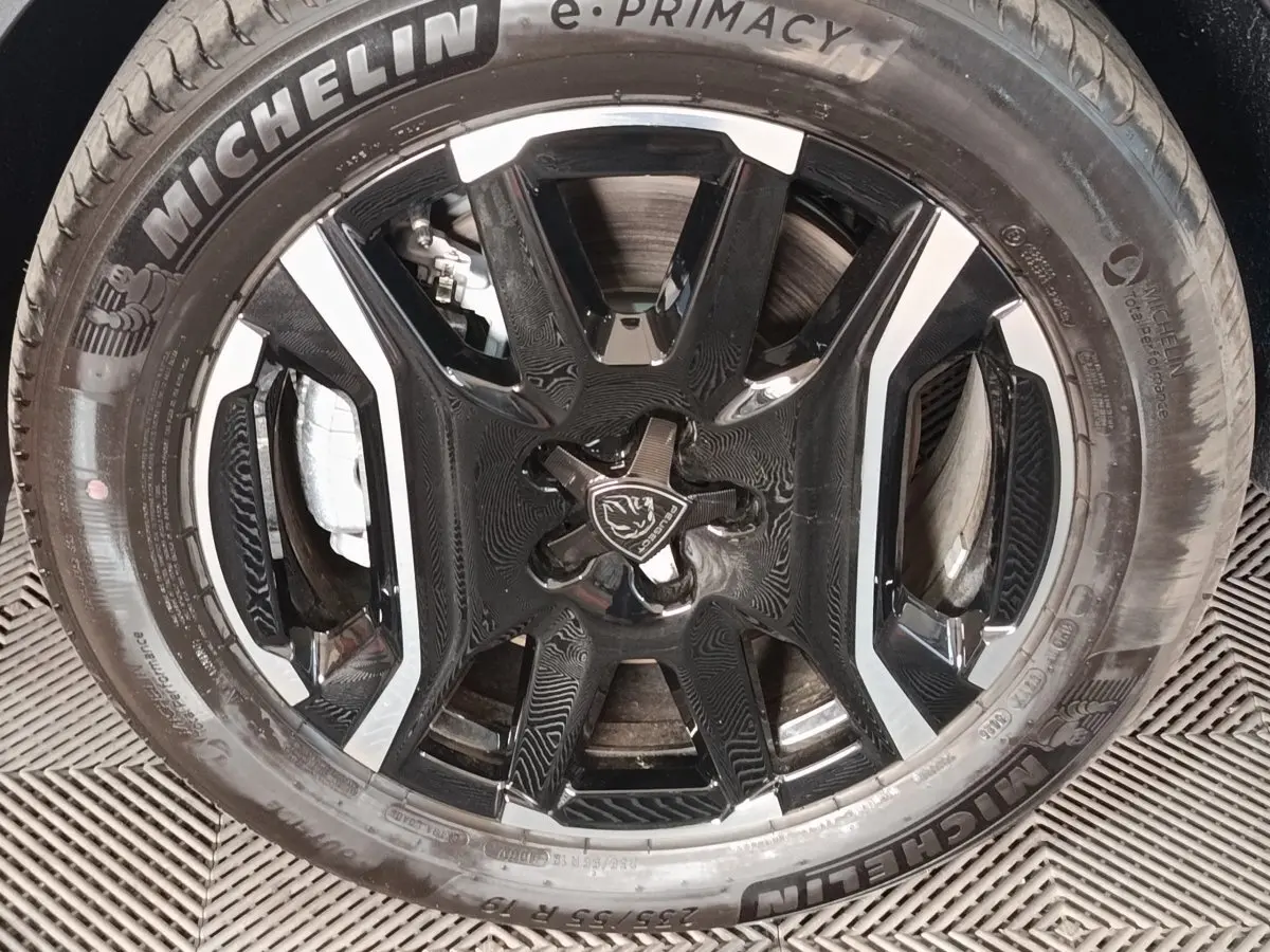 Gros plan sur la roue avant avec jante noire et argentée du Peugeot 5008 1.6 PHEV gris clair de 2026.