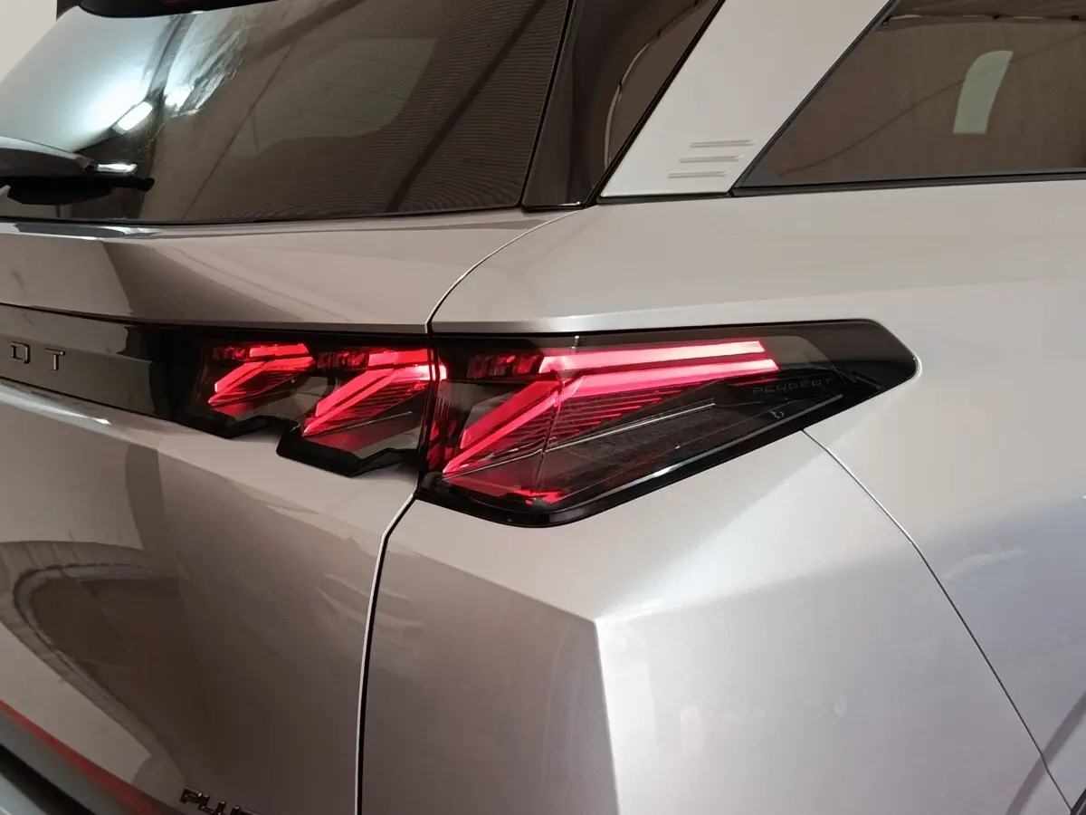 Gros plan sur le feu arrière droit rouge vif du Peugeot 5008 gris clair, soulignant la ligne anguleuse de la carrosserie.