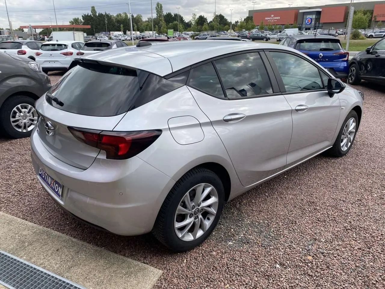 Opel Astra 2021 Sovereign Silver vue 3/4 arrière droit, jantes alliage 16'' gris argent et vitres surteintées.