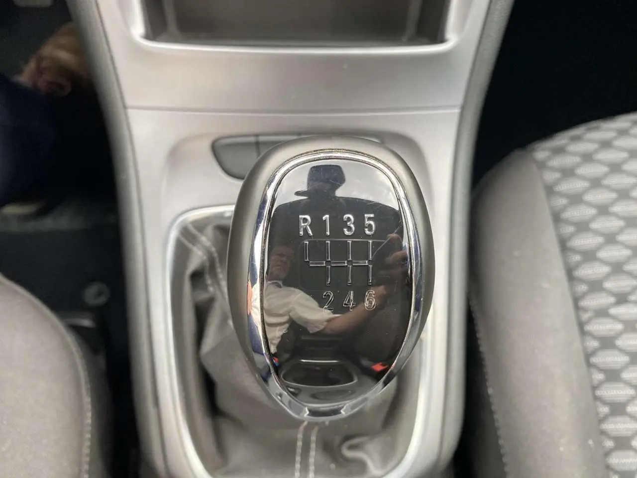 Le levier de vitesses manuel noir brillant de l'Opel Astra 1.2i Turbo Edition, entouré de la console grise.