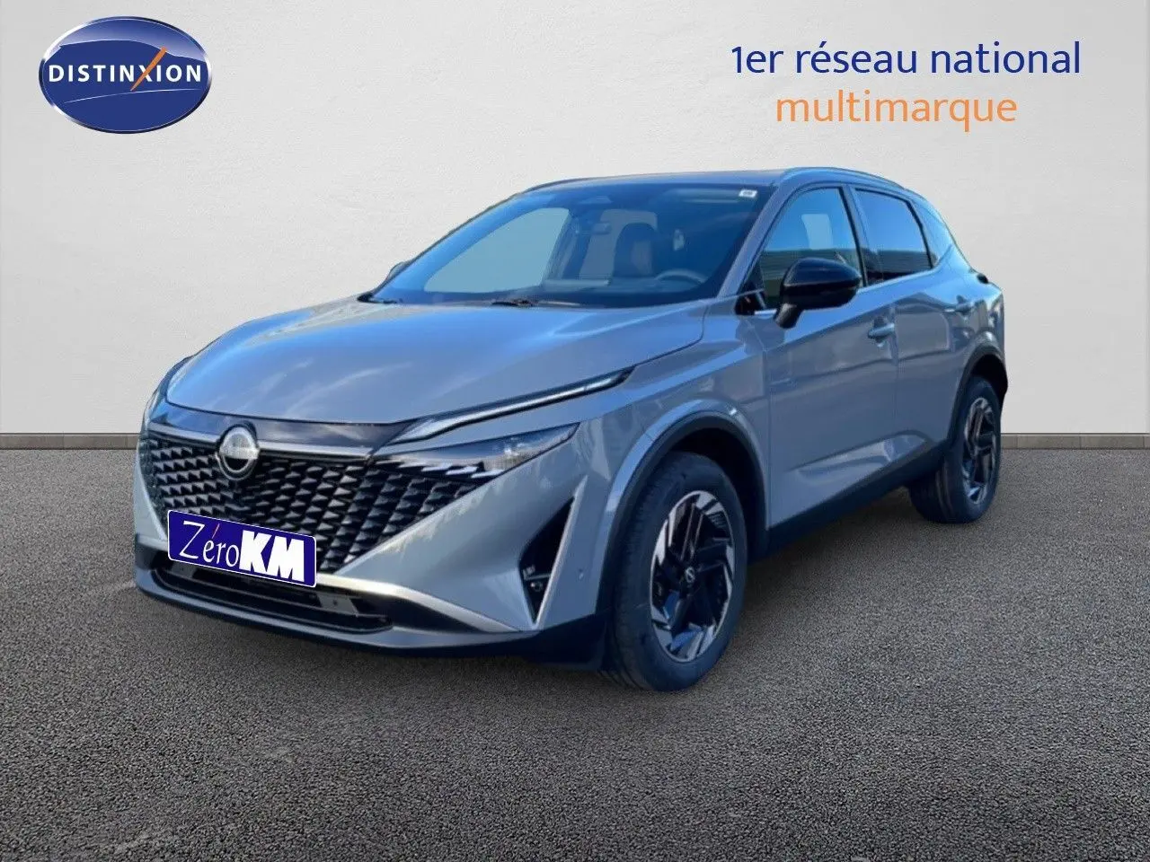 Nissan Qashqai 2025 gris argile métal en 3/4 avant droit, avec calandre noire et jantes bicolores.