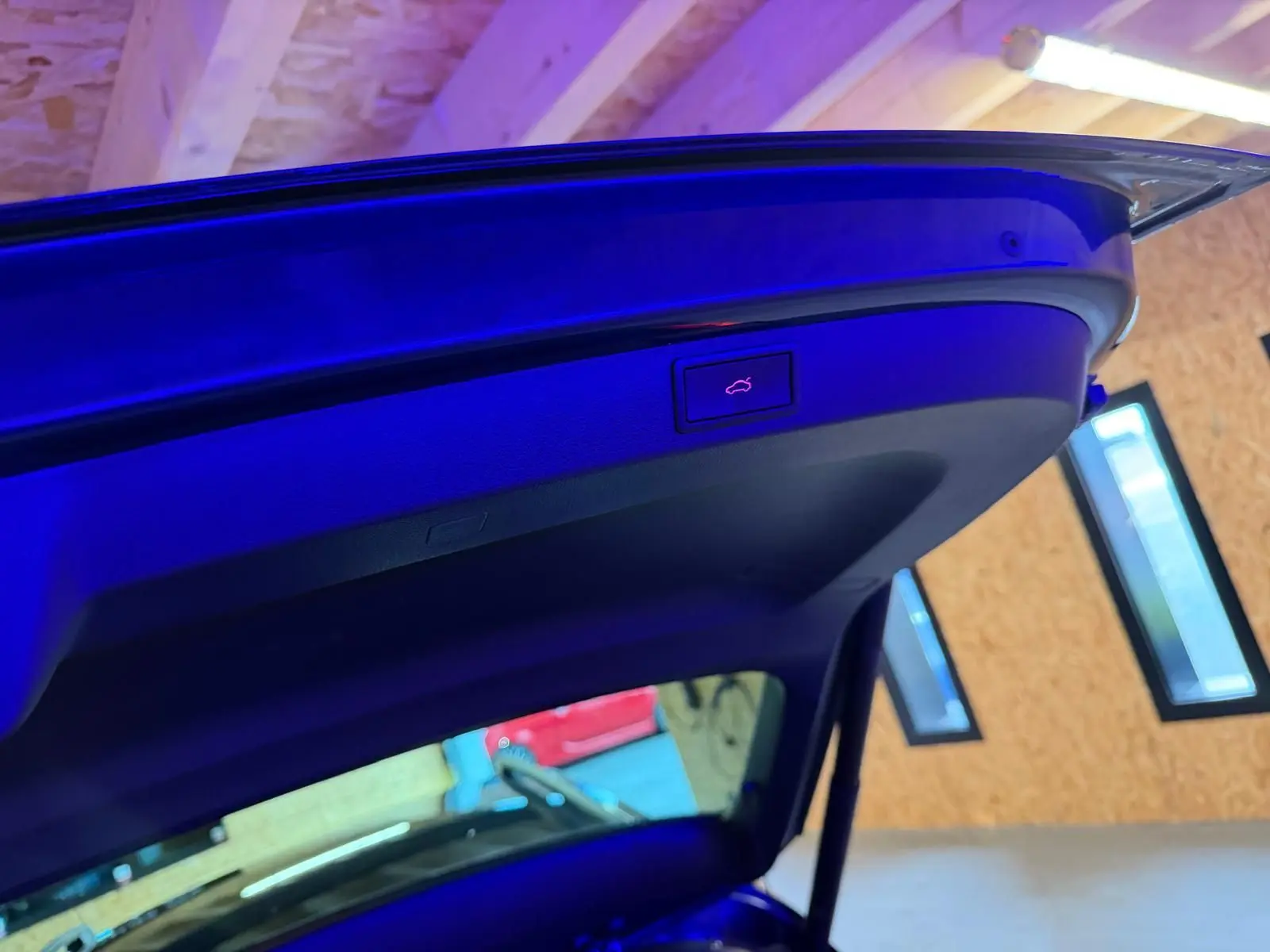 Bouton d'ouverture électrique du hayon sur la partie intérieure du coffre d'un Skoda Karoq bleu 2023.