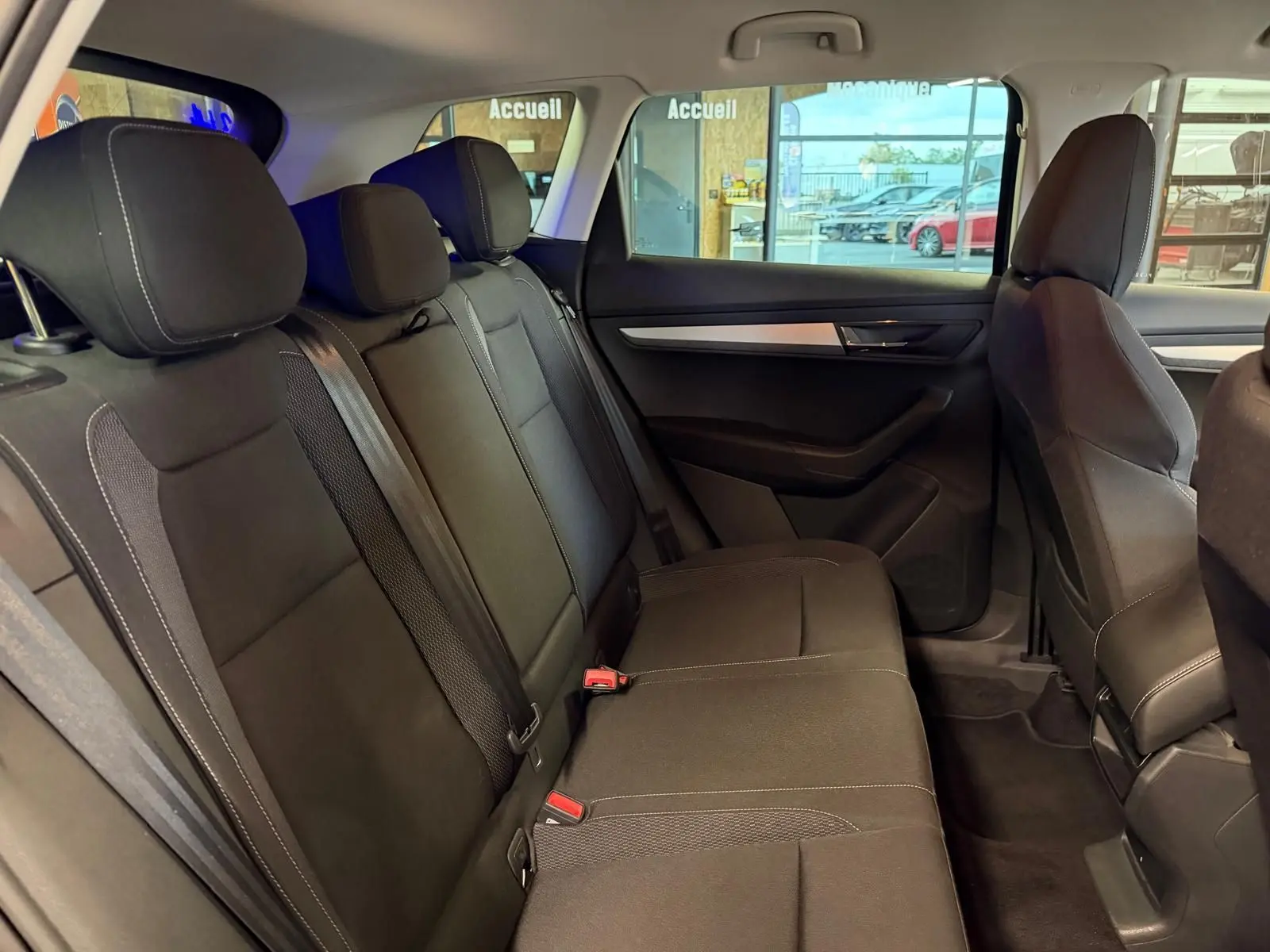 Vue intérieure côté droit des sièges arrière noirs du Skoda Karoq 2023 avec appuie-têtes et ceintures visibles.