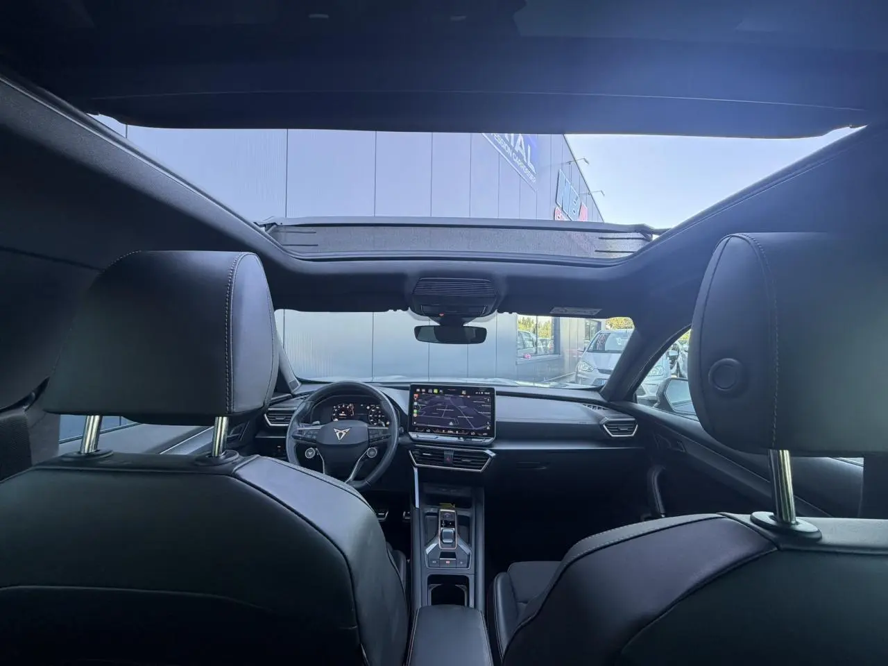 Vue intérieure avant du CUPRA Formentor 2025 gris, avec toit ouvrant panoramique et tableau de bord digital.