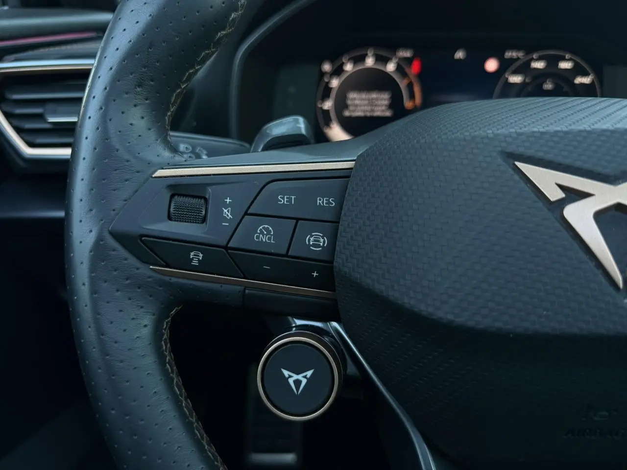 Gros plan sur le volant cuir perforé noir de la CUPRA Formentor 2025 avec commandes multifonctions et logo CUPRA central.