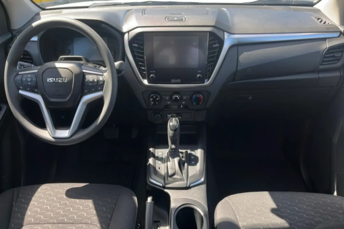 Vue intérieure frontale de l’Isuzu D-MAX 2026, tableau de bord noir avec écran tactile et volant multifonctions.