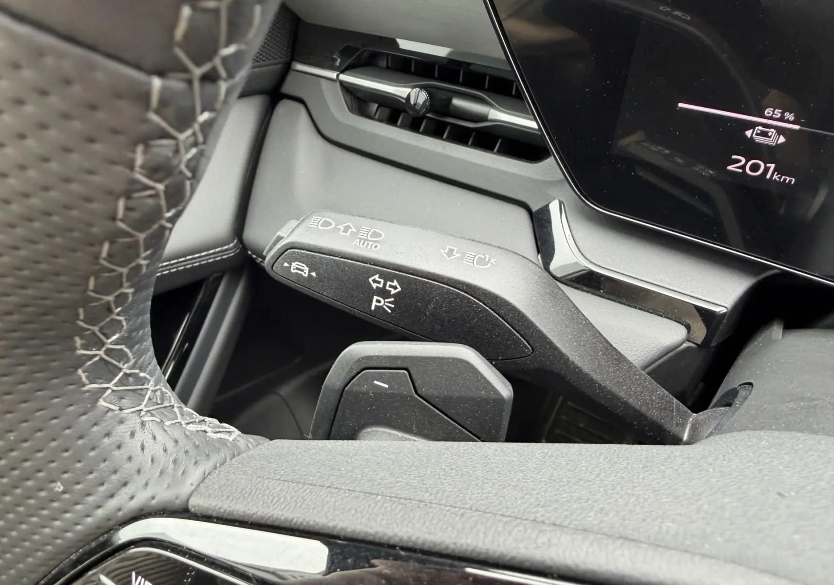 Gros plan sur la manette de clignotants et le volant perforé noir à coutures blanches de l'Audi Q6 e-tron 2024.