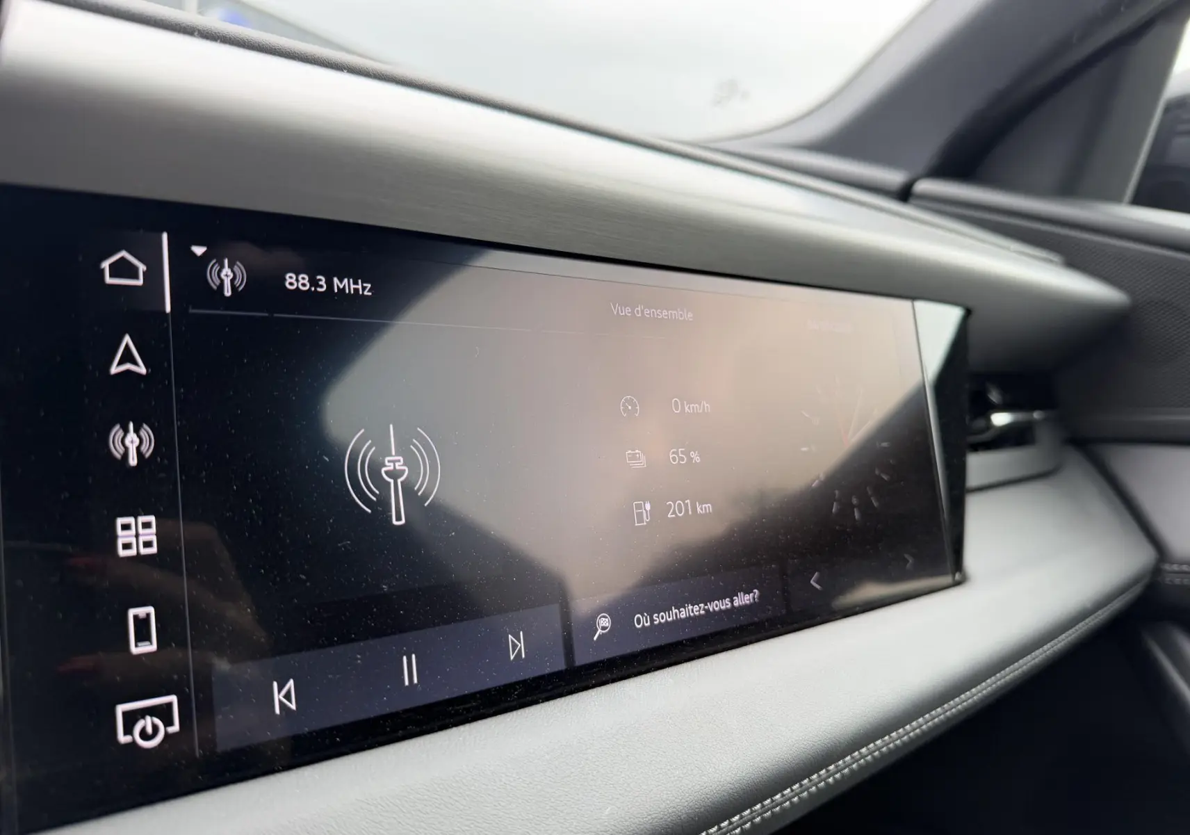 Écran tactile central de l’Audi Q6 e-tron 2024, affichant la radio et l’autonomie, intérieur gris clair.